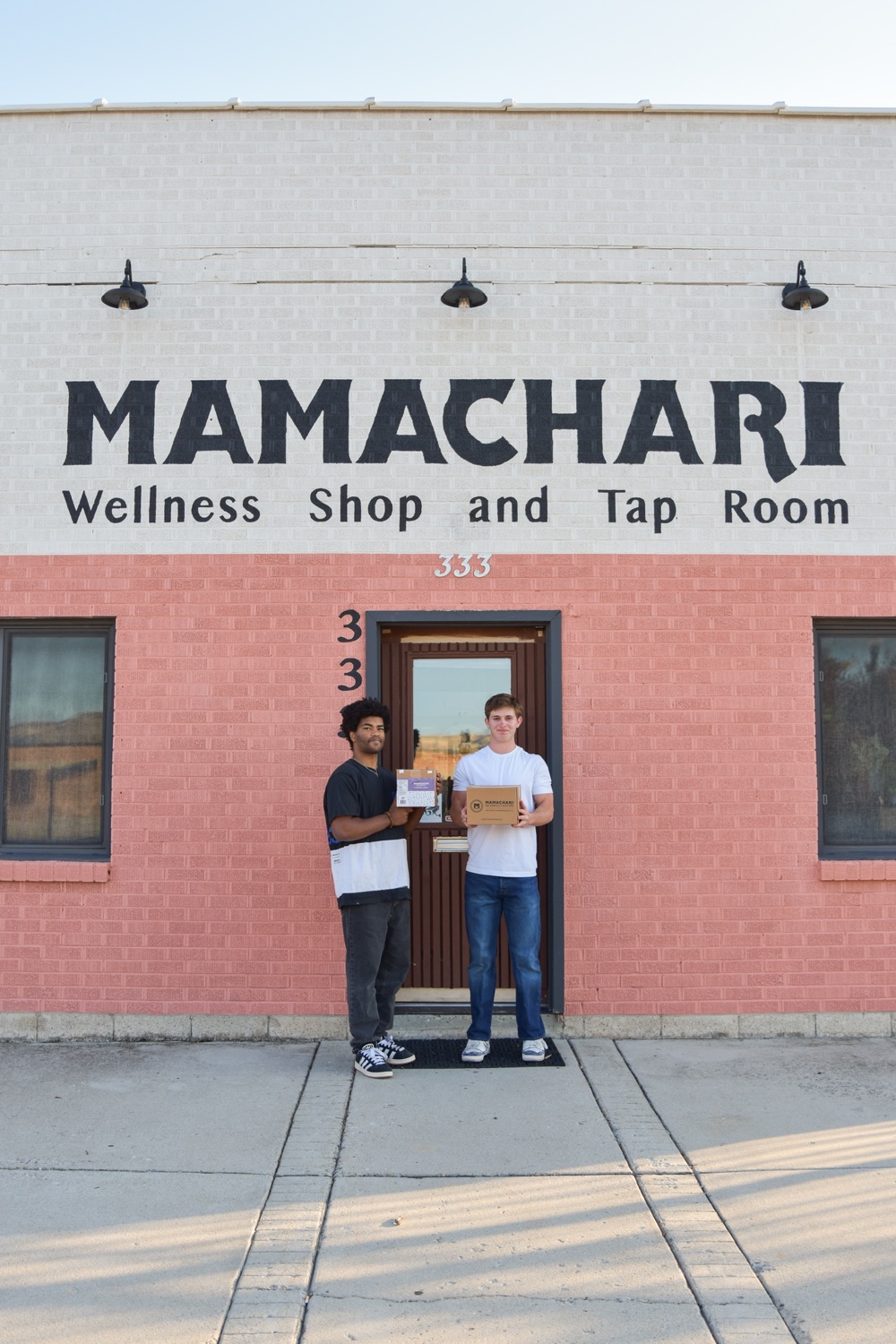 Two Campus Connect students standing outside Mamachari with product boxes